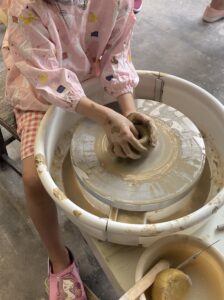 圓樸陶舍 一個小女孩正在參加親子課程，學習如何在輪子上製作陶器。
